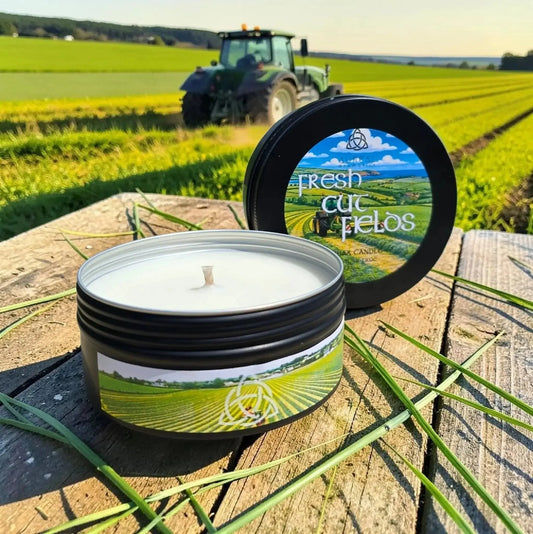 Fresh Cut Fields tin candle on a wooden table with a tractor in a field behind