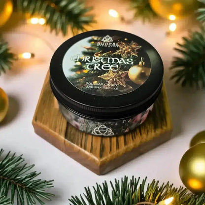 Christmas Tree candle in a black tin on wood, among pine and gold baubles