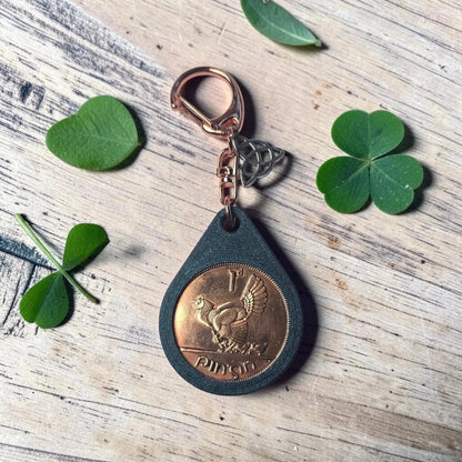 Irish penny keyring showing the hen side, with shamrock leaves on a wooden table