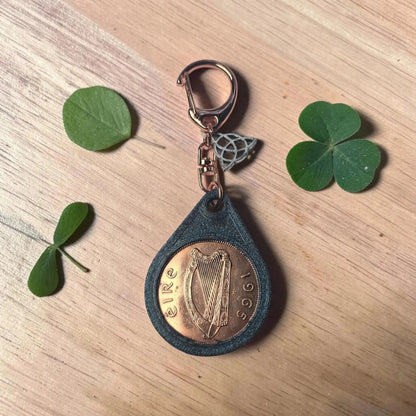 Irish penny keyring showing the harp side dated 1965, with shamrock leaves on wood