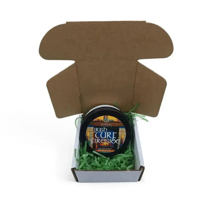 Irish Turf Fireside candle tin in an open brown mailer box with green paper shred