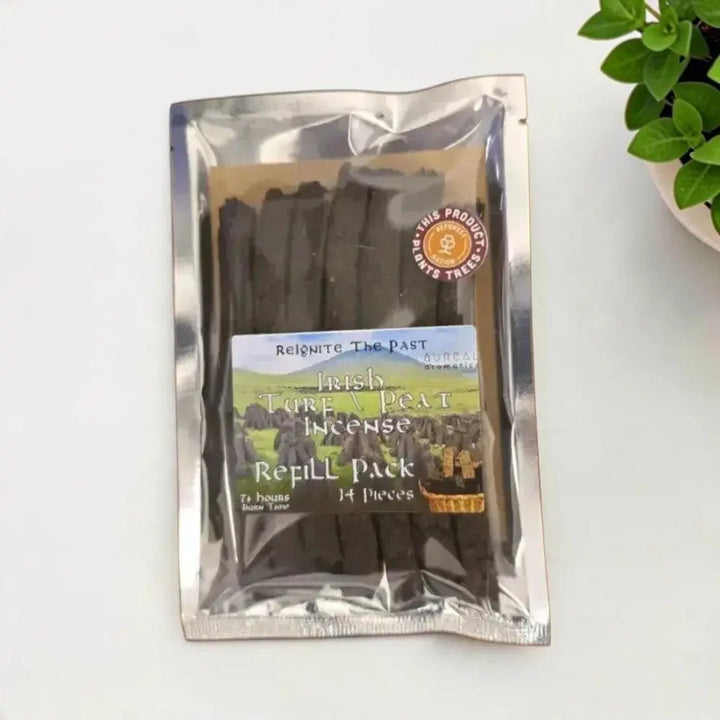 Irish Turf Peat Incense Refill Pack in a silver foil bag with a printed label, beside a green plant