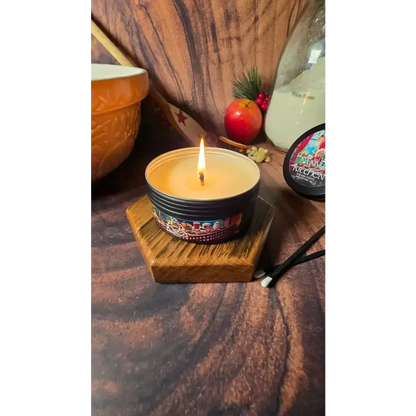 Lit Nanny's Kitchen tin candle on a wooden stand with a mixing bowl and apple behind