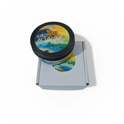 Wild Atlantic Way soy wax candle tin and a matching round sticker on a grey mailer box